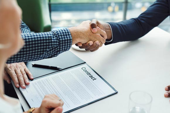 un conseiller et un client se serrent la main pour conclure un contrat d'entretien